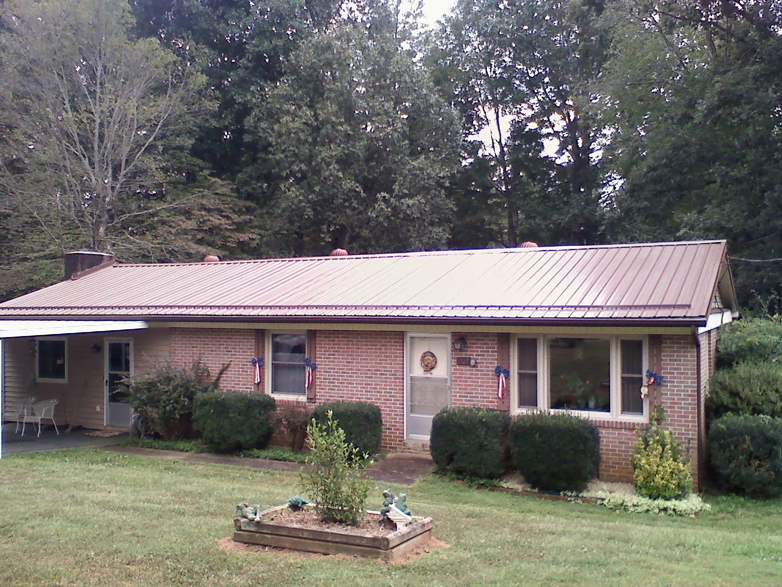 Bronze metal roof on a brick ranch home with a carport in Jackson Center
