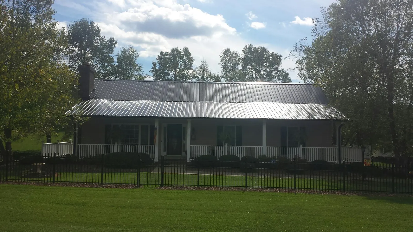 Gray metal roof on a brick ranch with a full width front porch — Gutter Guard Installation work by our crew in Jackson Center