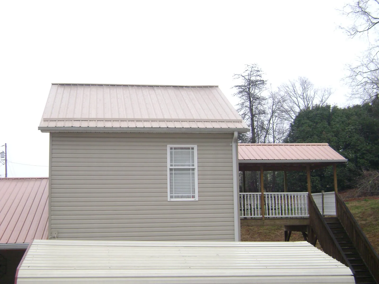 Tan metal roofs on a two story addition and attached porch, from a Roof Replacement job in Jackson Center